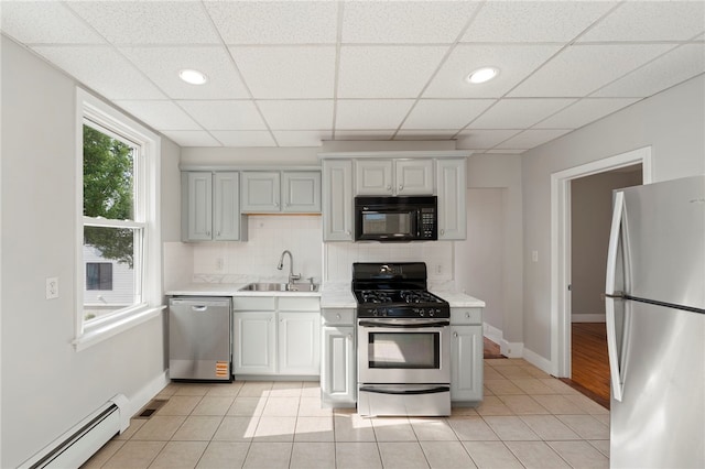 65 Lancaster St Unit 1, Providence, RI 02906 - kitchen with stainless steel appliances, a baseboard heating unit, light countertops, backsplash, and light tile patterned floors