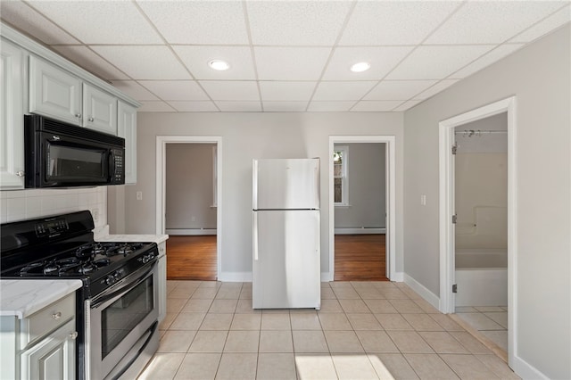 65 Lancaster St Unit 1, Providence, RI 02906 - kitchen featuring black microwave, freestanding refrigerator, stainless steel gas stove, light tile patterned floors, and a baseboard radiator