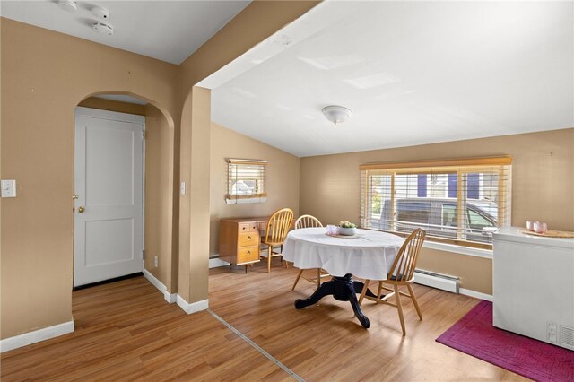 21 Cypress Ave, Tiverton, RI 02878 - dining space featuring arched walkways, light wood-style flooring, vaulted ceiling, and a baseboard heating unit