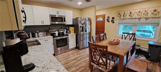 26 Morton Ave, Johnston, RI 02919 - kitchen with stainless steel appliances, white cabinetry, a baseboard heating unit, light wood-type flooring, and ceiling fan