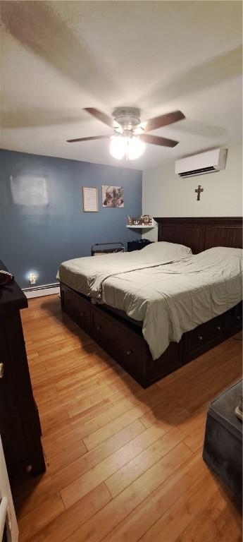 26 Morton Ave, Johnston, RI 02919 - bedroom featuring an AC wall unit, a baseboard heating unit, light wood-style floors, and a ceiling fan