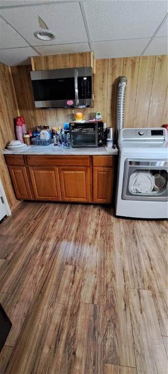 26 Morton Ave, Johnston, RI 02919 - kitchen featuring washer / dryer, stainless steel microwave, a paneled ceiling, wood finished floors, and wooden walls