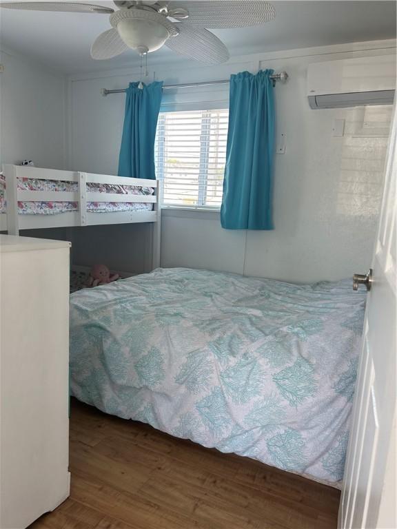 854 Matunuck Beach Rd, South Kingstown, RI 02879 - bedroom with a wall mounted AC, wood finished floors, and a ceiling fan