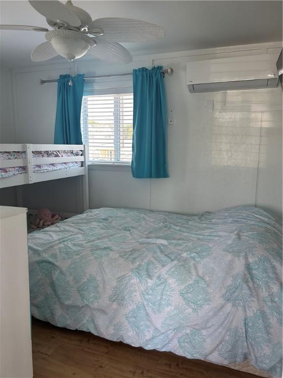 854 Matunuck Beach Rd, South Kingstown, RI 02879 - bedroom featuring a wall mounted AC, wood finished floors, and ceiling fan