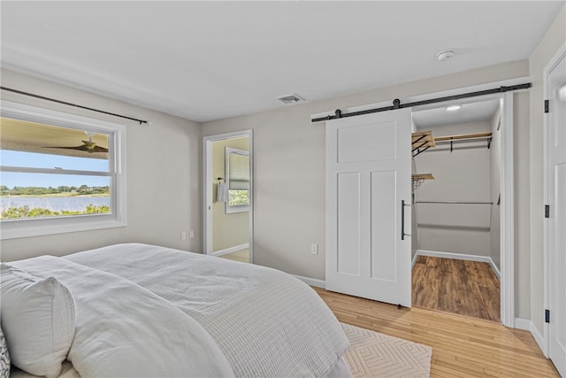 212 Round Pond Rd, Little Compton, RI 02837 - bedroom with a barn door, light wood-style flooring, and a walk in closet