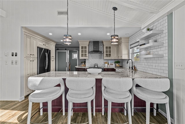 212 Round Pond Rd, Little Compton, RI 02837 - kitchen with black refrigerator, wall chimney range hood, cream cabinetry, light wood-style floors, and recessed lighting