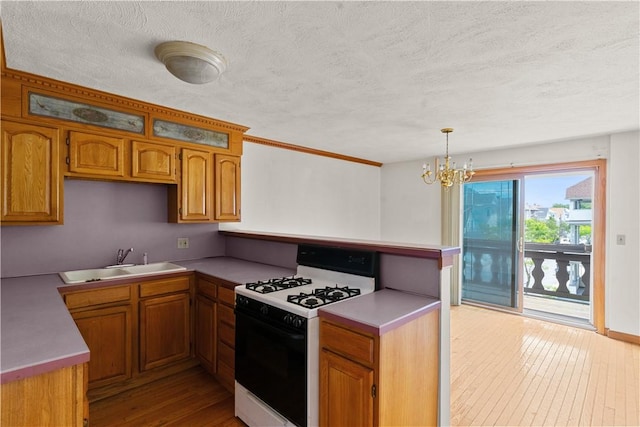 129 Academy Ave, Providence, RI 02908 - kitchen featuring white gas stove, a peninsula, light wood-style flooring, brown cabinetry, and a chandelier