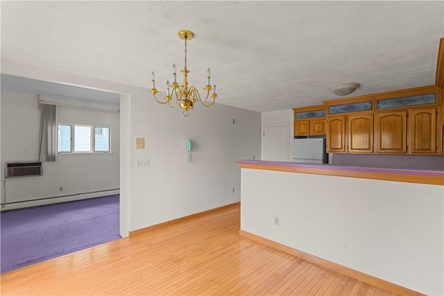 129 Academy Ave, Providence, RI 02908 - kitchen with fridge, a baseboard radiator, brown cabinetry, a chandelier, and a wall mounted AC