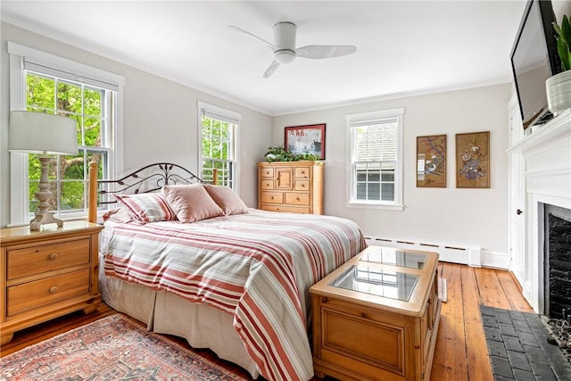 47 Second St, Newport, RI 02840 - bedroom with a baseboard heating unit, hardwood / wood-style floors, a fireplace with flush hearth, ornamental molding, and a ceiling fan
