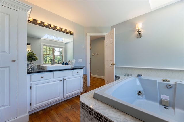 170 W Beach Rd, Charlestown, RI 02813 - bathroom featuring vanity, a jetted tub, wood finished floors, and a skylight