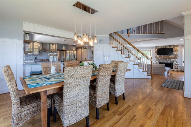 170 W Beach Rd, Charlestown, RI 02813 - dining room featuring light wood-style floors, stairs, a stone fireplace, and ornamental molding