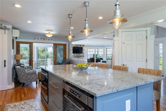 170 W Beach Rd, Charlestown, RI 02813 - kitchen featuring open floor plan, crown molding, wood finished floors, light stone countertops, and pendant lighting