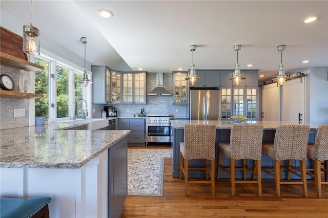 170 W Beach Rd, Charlestown, RI 02813 - kitchen featuring appliances with stainless steel finishes, wall chimney range hood, wood finished floors, gray cabinets, and decorative backsplash