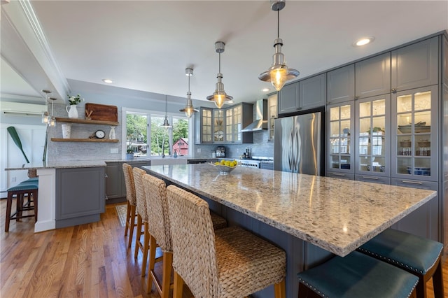 170 W Beach Rd, Charlestown, RI 02813 - kitchen with freestanding refrigerator, wall chimney range hood, gray cabinets, light wood-type flooring, and glass insert cabinets
