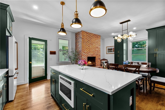 93 E Main Rd, Portsmouth, RI 02871 - kitchen featuring green cabinetry, built in microwave, freestanding refrigerator, a brick fireplace, and wood finished floors