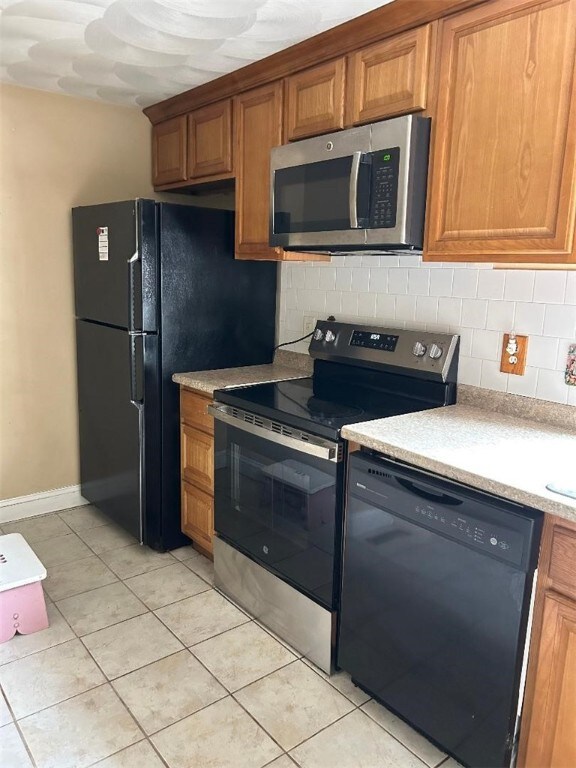 163 Reynolds Ave, Warwick, RI 02889 - kitchen featuring black appliances, brown cabinets, decorative backsplash, light tile patterned floors, and light countertops