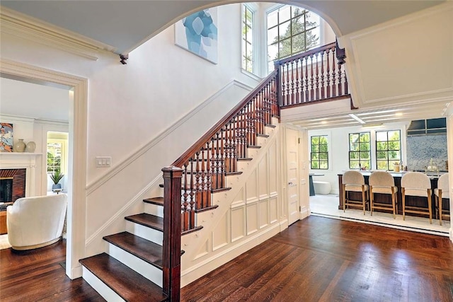 290 Blackstone Blvd, Providence, RI 02906 - stairs featuring wood finished floors, ornamental molding, a decorative wall, a fireplace, and arched walkways