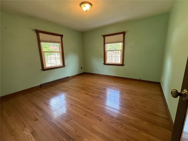 26 Flora Ave, Woonsocket, RI 02895 - empty room featuring healthy amount of natural light, wood finished floors, and a baseboard radiator