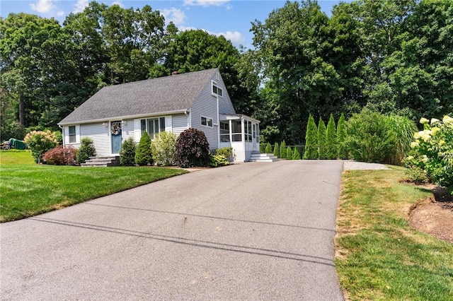 32 Spencer Rd, Smithfield, RI 02828 - view of front facade featuring roof with shingles, a sunroom, a front lawn, entry steps, and view of wooded area