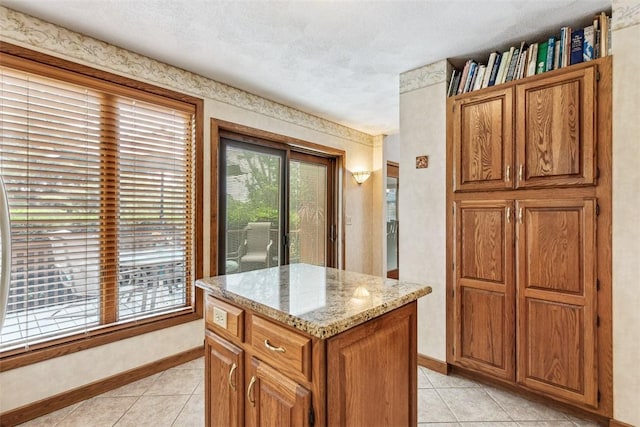 4 Wilbur Rd, Lincoln, RI 02865 - kitchen with light tile patterned flooring, brown cabinets, light stone counters, a kitchen island, and a textured ceiling