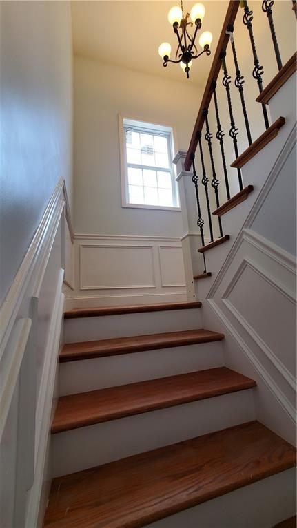 43 Amsterdam St, Providence, RI 02909 - stairs with a chandelier, a decorative wall, and wainscoting