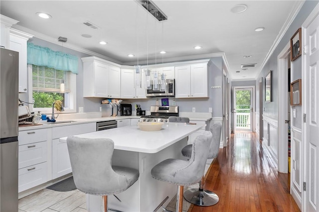 43 Amsterdam St, Providence, RI 02909 - kitchen with stainless steel appliances, plenty of natural light, crown molding, white cabinetry, and a breakfast bar area