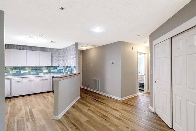 2 School St Unit 334, Lincoln, RI 02802 - kitchen featuring white cabinets, light wood finished floors, tasteful backsplash, light countertops, and a peninsula