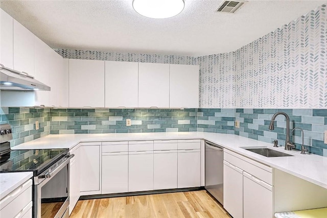 2 School St Unit 334, Lincoln, RI 02802 - kitchen with stainless steel appliances, under cabinet range hood, light countertops, light wood-type flooring, and backsplash