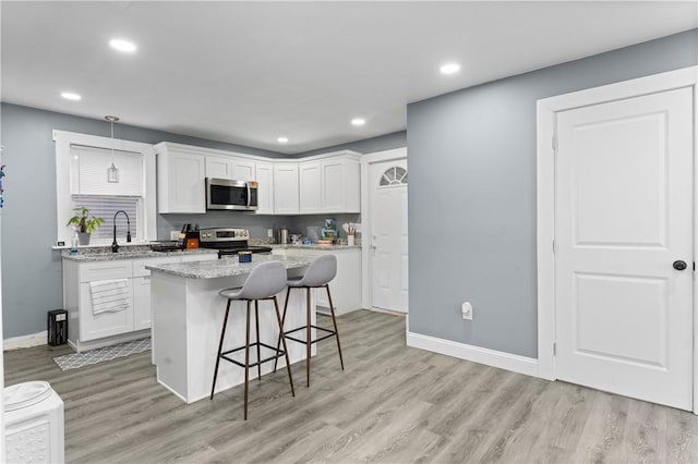 31 Stadden St, Providence, RI 02907 - kitchen featuring appliances with stainless steel finishes, light wood-style floors, white cabinets, a kitchen breakfast bar, and a center island