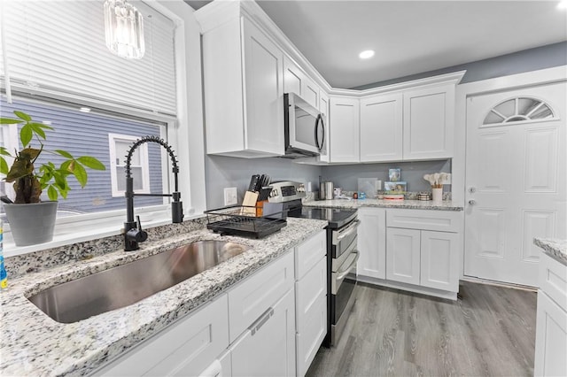 31 Stadden St, Providence, RI 02907 - kitchen with appliances with stainless steel finishes, white cabinets, light wood finished floors, light stone countertops, and recessed lighting