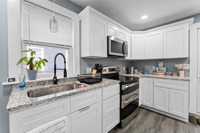 31 Stadden St, Providence, RI 02907 - kitchen featuring appliances with stainless steel finishes, white cabinets, dark wood-style floors, pendant lighting, and light stone countertops
