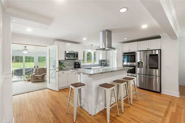 15 Bestwick Trl, Coventry, RI 02816 - kitchen featuring appliances with stainless steel finishes, island exhaust hood, ornamental molding, light wood-style flooring, and a kitchen bar