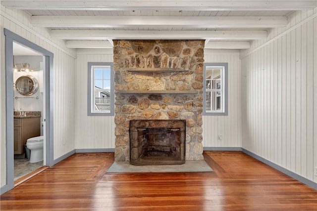 1 Barney Ave, South Kingstown, RI 02879 - unfurnished living room with hardwood / wood-style flooring, a stone fireplace, and a wooden ceiling with exposed beams