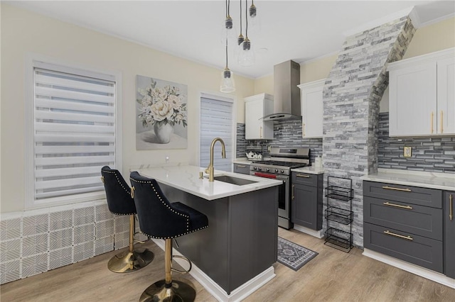 155 Early St, Providence, RI 02907 - kitchen featuring stainless steel gas range, wall chimney exhaust hood, light wood-style floors, backsplash, and white cabinets