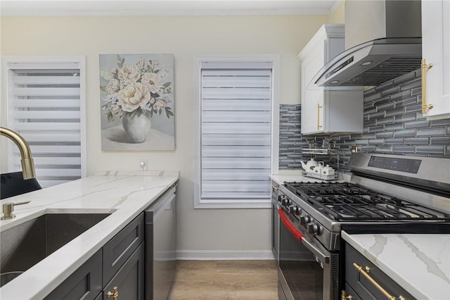155 Early St, Providence, RI 02907 - kitchen with stainless steel gas stove, wall chimney exhaust hood, dishwashing machine, decorative backsplash, and light wood finished floors