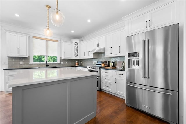 96 Evergreen St, Cumberland, RI 02864 - kitchen featuring appliances with stainless steel finishes, under cabinet range hood, dark wood-type flooring, white cabinetry, and ornamental molding