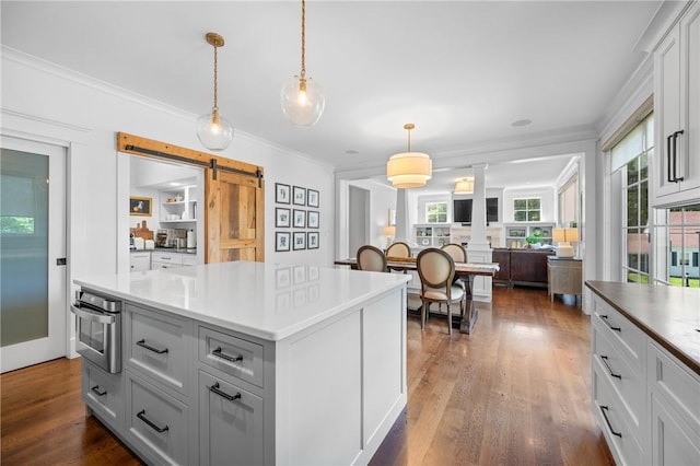 96 Evergreen St, Cumberland, RI 02864 - kitchen with a barn door, crown molding, a kitchen island, dark wood-type flooring, and ornate columns