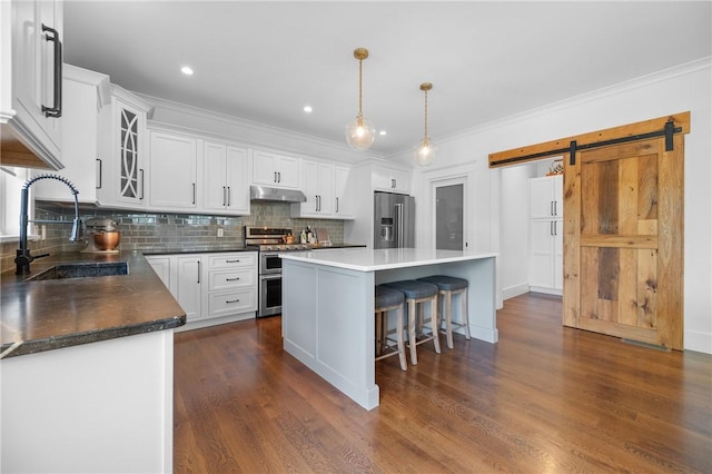 96 Evergreen St, Cumberland, RI 02864 - kitchen featuring stainless steel appliances, under cabinet range hood, a kitchen island, a barn door, and decorative backsplash