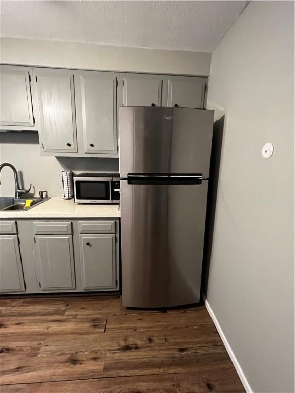 494 Putnam Pike Unit A12, Smithfield, RI 02828 - kitchen with stainless steel appliances, gray cabinetry, light countertops, dark wood finished floors, and a textured ceiling