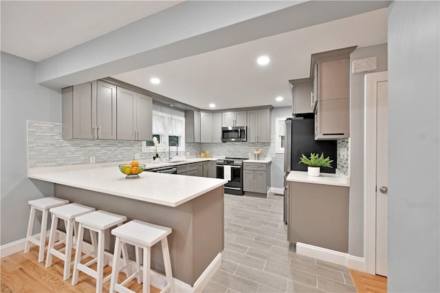 12 Leddy Rd, Cumberland, RI 02864 - kitchen with stainless steel appliances, gray cabinetry, a peninsula, decorative backsplash, and light countertops