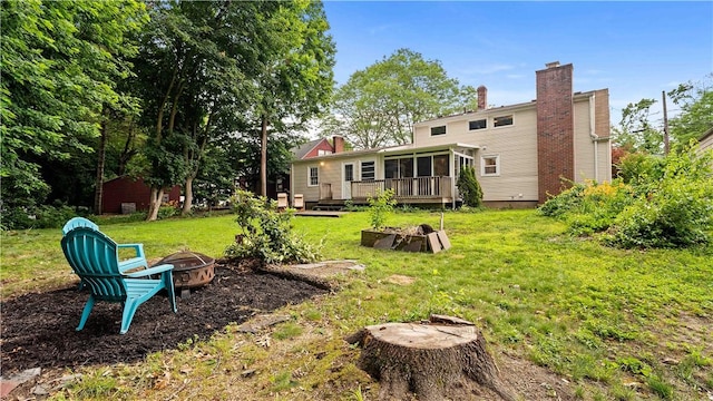 74 Algonquin Rd, East Providence, RI 02916 - back of property with an outdoor fire pit, a chimney, a deck, a yard, and a sunroom