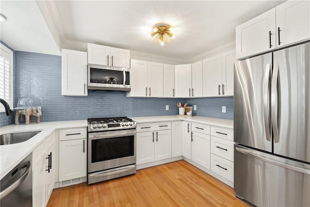 33 Arbor Dr Unit 27, Providence, RI 02908 - kitchen with appliances with stainless steel finishes, light countertops, decorative backsplash, light wood-style flooring, and crown molding