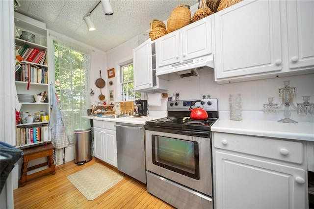33 Kay St, Newport, RI 02840 - kitchen with stainless steel appliances, under cabinet range hood, white cabinetry, and light countertops