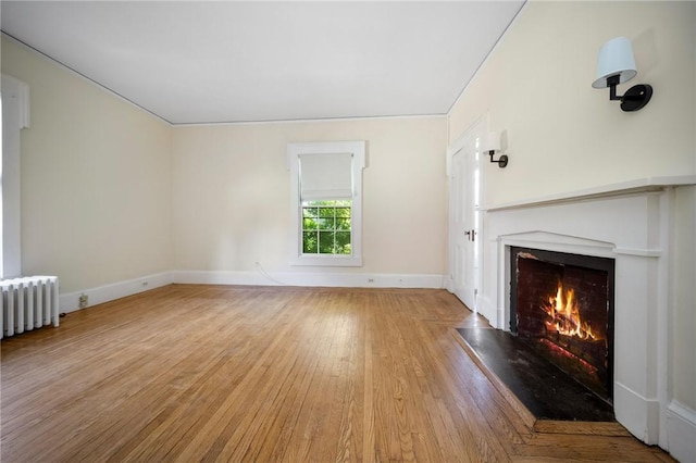 33 Kay St, Newport, RI 02840 - unfurnished living room featuring wood finished floors, a warm lit fireplace, and radiator heating unit