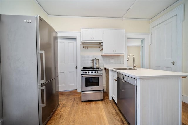 33 Kay St, Newport, RI 02840 - kitchen with stainless steel appliances, a peninsula, light countertops, light wood-type flooring, and white cabinetry