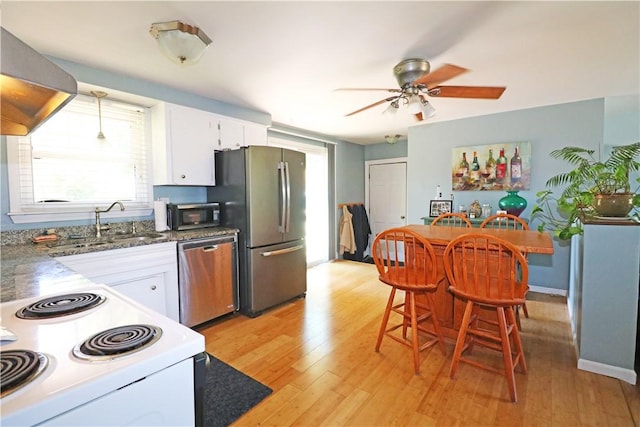 27 Louise Dr, Tiverton, RI 02878 - kitchen featuring appliances with stainless steel finishes, wall chimney exhaust hood, white cabinets, ceiling fan, and light wood-style flooring