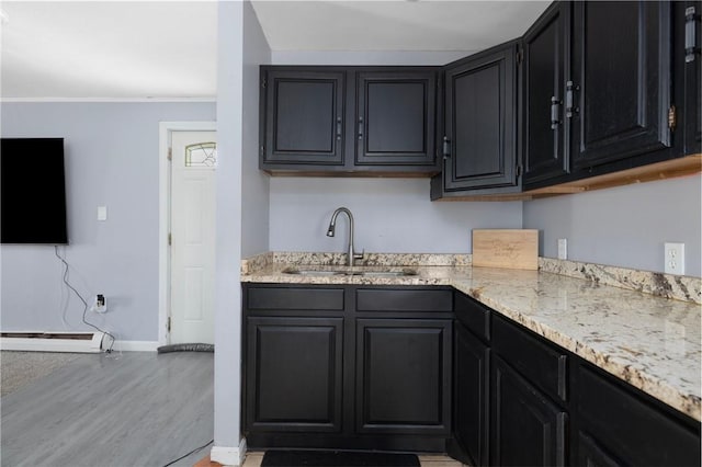40 W Cole St, Pawtucket, RI 02861 - kitchen with light wood finished floors, dark cabinetry, ornamental molding, light stone countertops, and a baseboard heating unit