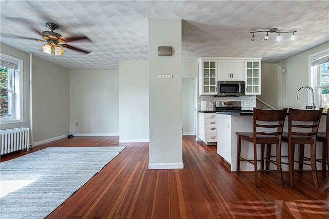 9 Locust St, Providence, RI 02906 - kitchen featuring appliances with stainless steel finishes, white cabinets, a kitchen breakfast bar, glass insert cabinets, and dark wood-style floors