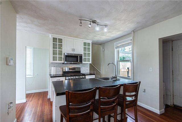 9 Locust St, Providence, RI 02906 - kitchen with appliances with stainless steel finishes, dark countertops, dark wood-style floors, white cabinetry, and tasteful backsplash