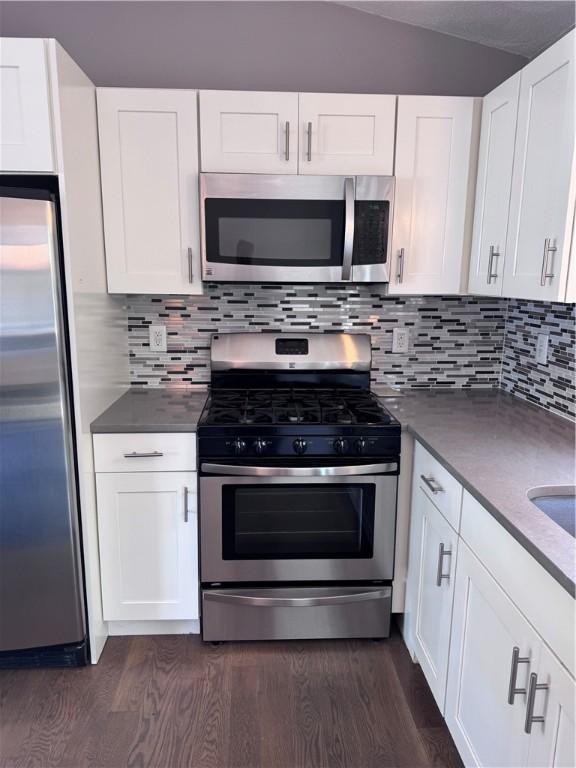 27 Brook St, West Warwick, RI 02893 - kitchen with appliances with stainless steel finishes, dark wood finished floors, white cabinets, and tasteful backsplash